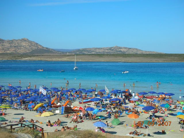 La spiaggia di stintino, e piu' in la', spunta dal mare l'usola dell'Asinara, o isola Sinuaria.